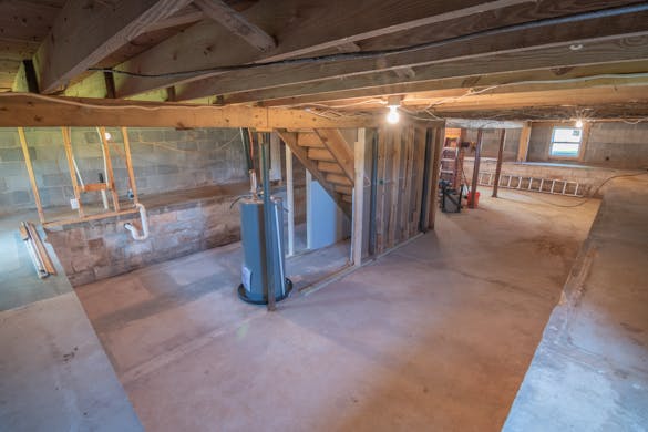 Basement with exposed plumbing pipes showing where a sump pump would be installed