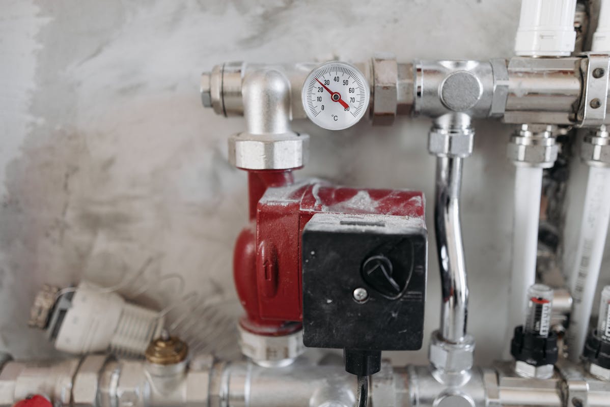 Close-up of industrial plumbing system with pressure gauge and steel pipes, similar to sump pump mechanics